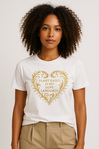 Person wearing a white t-shirt with gold graphic that reads Plant Based is My Love Language, plain background