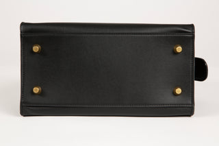 Image of the bottom of a Lavāda vegan leather handbag in black featuring natural brass feet.
