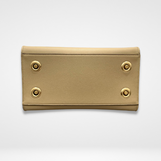 Image of Lavāda vegan leather handbag overlay bottom in tan featuring natural brass feet and grommets.