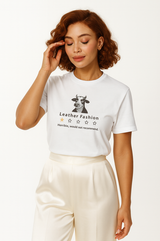 Woman wearing a white t-shirt with black and gold funny graphic featuring a cow that gives leather fashion one star 