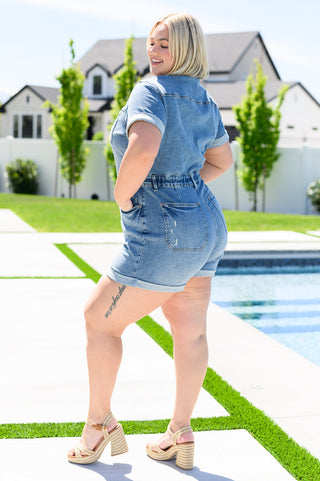 Three quarter view of woman wearing a denim jumpsuit romper by a poolside