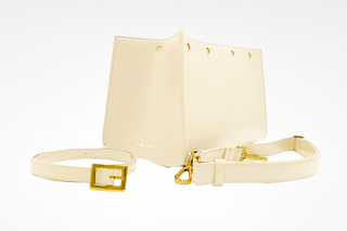 Off white interchangeable accessories for Lavada vegan leather handbag, includes outer cover, strap, and belt. Shown against white background.