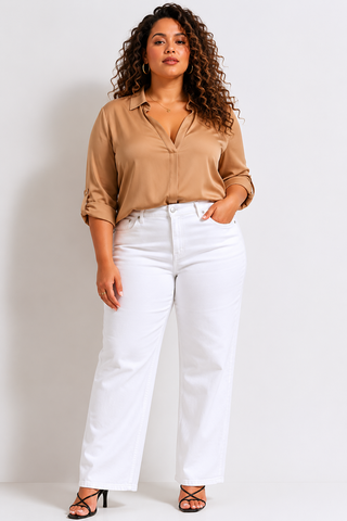 Woman wearing a beige blouse and white pants against a plain background