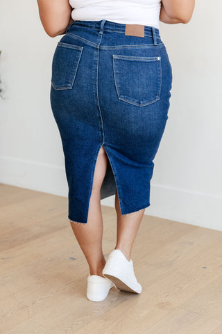 Rear view of woman wearing a dark blue denim midi skirt with a white background