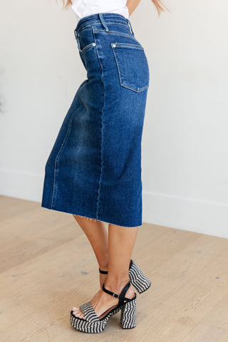 Side view of woman wearing a blue denim pencil midi skirt with a white background