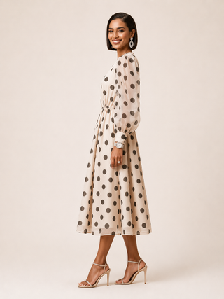 Side view of woman wearing a gray and white polka dot dress on a plain background