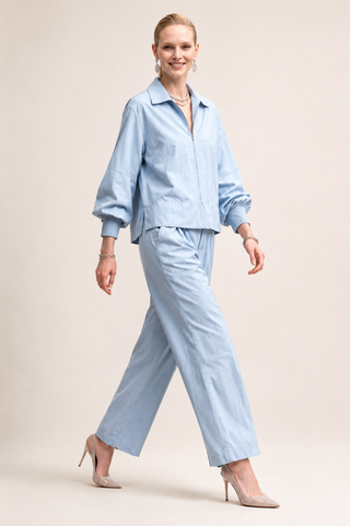 Woman wearing a pastel blue jacket and pants suit, featuring roomy fit and balloon style puffy sleeves 