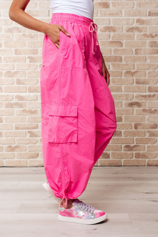 Side view of person wearing bright pink cargo pants against a brick wall.